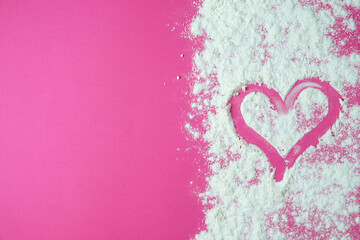 Scattered flour on a pink space and a drawing of a heart, close-up. Heart on a pink background. Valentine's day background. 