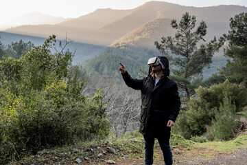man using technological virtual reality glasses in mountain and forest