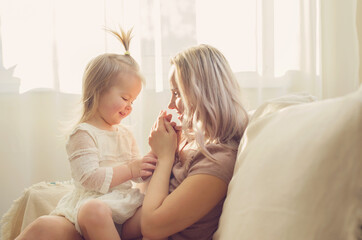 Mother and  daughter toddler playing, kissing, hugging  and smiling, enjoy at the sofa, spending time at home. Moments of tenderness . Happy loving family. Good time at home. Family single mother
