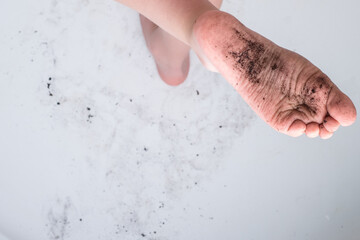 The child raising a dirty foot in the ground. In the bathroom on a white background