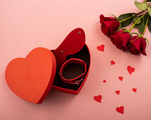Bdsm set in a box in the form of a heart and red roses on a pink background. Valentine's day gift idea