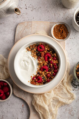 Petit déjeuner avec bol de granola, yaourts et framboises