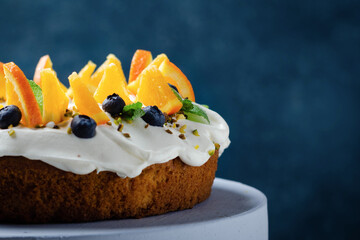 Orange fruit cake and blueberries on rustic background.