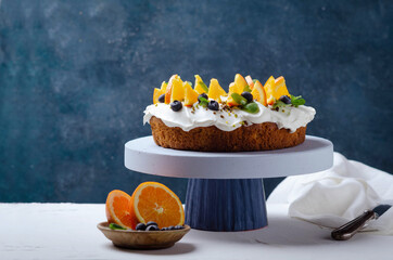 Orange fruit cake and blueberries on rustic background.