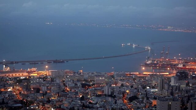 Beautiful evening view of the city of Haifa from the mountain. Large Israeli port. Street lights illuminate the streets and the city.