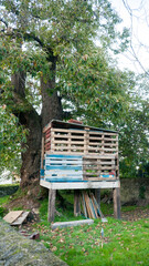 Cabaña hecha con palés junto a árbol en jardín