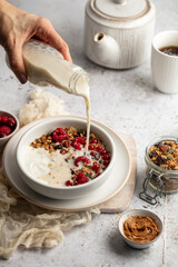 Petit déjeuner avec bol de granola, yaourts et framboises