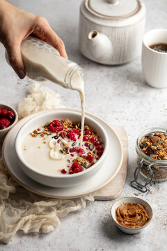 Petit d&eacute;jeuner avec bol de granola, yaourts et framboises