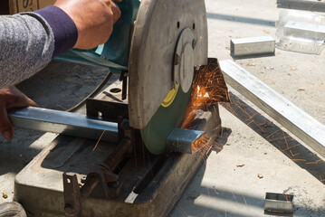 Unsafe Worker Cutting Metal Construction with no Protection Uniform with Electric Wheel Fabric Cutting Machine in the Construction Site.
