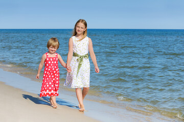 Two cute little girls walking on the beach