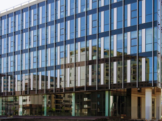 Reflection of multi-level residential buildings in the large glass wall of a modern office construction 