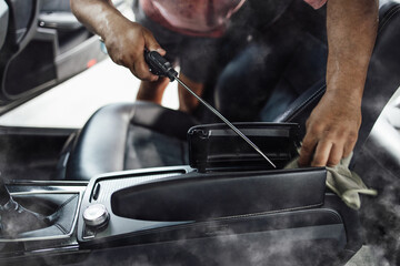 Car wash service worker wet cleaning vehicle interior and seats. Old car restoration work.