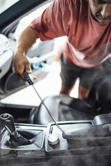 Car wash service worker wet cleaning vehicle interior and seats. Old car restoration work.