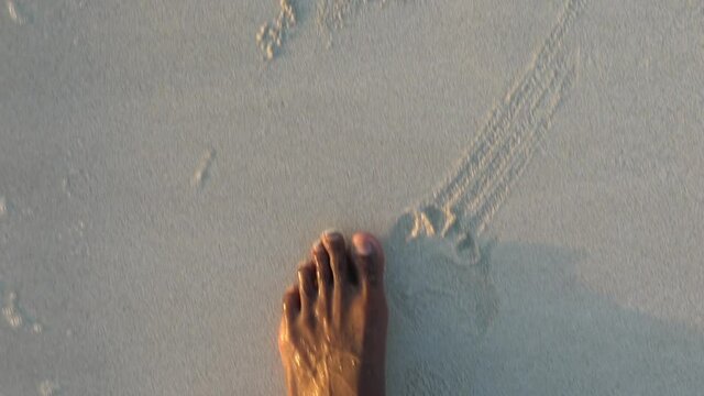 Close up view of an adult black male walking on a beautiful beach during sunset. Slow motion of an African American male walking on the beach.  