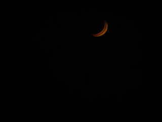 Close-up photo of the crescent moon. Double exposure view of red moon in black background.
Selective focus.