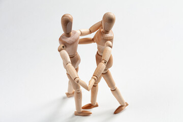 two wooden mannequins dancing and holding hands