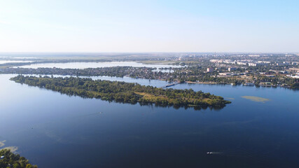 Drone fly over waving river of blue color surrounded by local village with various buildings and Wetland and marsh habitat with a reedbed of Common Reed aerial view.