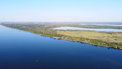 Drone fly over waving river of blue color surrounded by local village with various buildings and Wetland and marsh habitat with a reedbed of Common Reed aerial view.