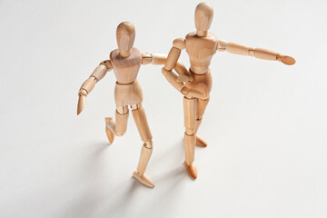 two wooden mannequins holding hands and stepping forward