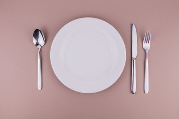 table setting plate fork spoon and knife on gray background white plate