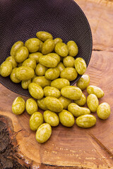 Nuts, almonds in green tea glaze, Matcha spilling out of a dark cup onto a wooden background