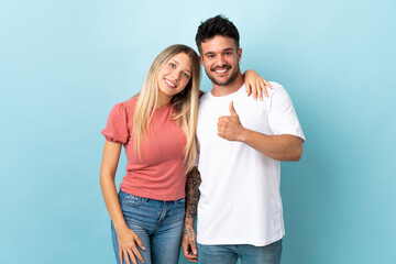 Fototapeta premium Young caucasian couple isolated on blue background giving a thumbs up gesture