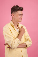 Sexy smiling handsome man with crossed arms on pink background.