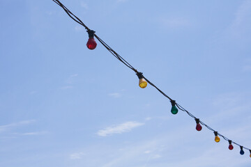 String Of Coloured Lights Against Blue Sky In Coastal Town