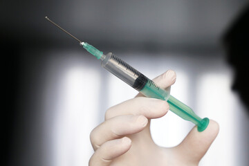 Syringe in hand close up, doctor in protective gloves preparing to injection. Concept of vaccination during covid-19 pandemic