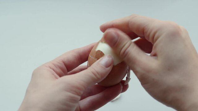 Hands peel eggshells from boiled eggs, close-up. Hard boiled egg opening, protein source. Healthy breakfast. Easter concept