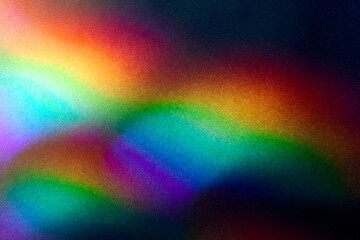 Blurred Bright multicolored glare on dark rough textured cardboard. Soft rainbow light. Abstract colorful background. Unusual light effect.