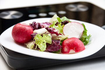 some salad on white plate standing on black scales on white background