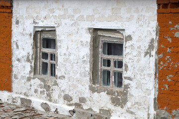 Fototapeta na wymiar Decrepit building with small windows. Housing of poor people.