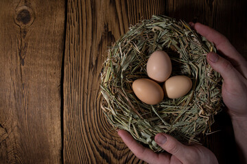 easter basket with eggs in hands on vintage wooden background