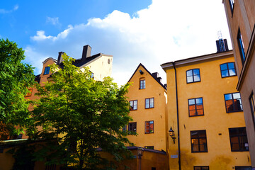 Cozy courtyard with in yellow houses and green trees in the Old Town of Stockholm. Sunny summer day in Sweden.