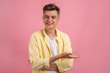 Obraz premium Happy smiling young man presenting and showing your text or product isolated on pink background