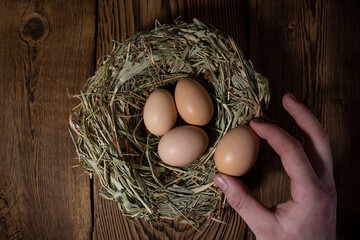 easter basket with eggs in hands on vintage wooden background