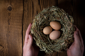 easter basket with eggs in hands on vintage wooden background with copy space