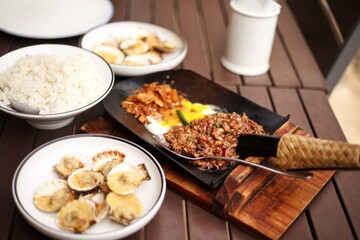traditional Philippine food, sisig, fried pork and baked scallops, rice bowl on the wooden table
