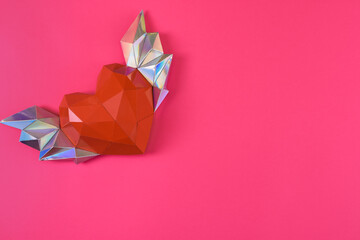 Red polygonal paper heart with wings on a pink background. space for writing