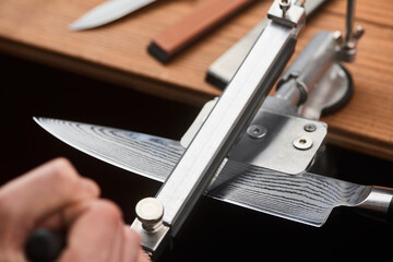 Close-up on man's hand using a manual machine to sharpen a Japanese knife