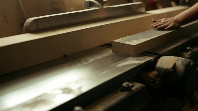 Unknown carpenter cutting wood in workshop. Man preparing plank in studio