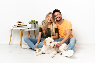 Young caucasian couple with dog staying at home hugging