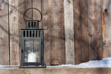 Black metal candle lantern on a wooden backdrop