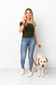 Young Caucasian Woman Walking The Dog Isolated On White Background Showing Ok Sign With Fingers