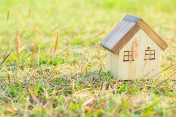 Modern miniature wood house model on grass background