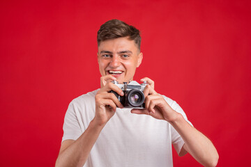 Obraz premium Say cheese! Young man take photo with retro dslr camera looking at camera over gray abackground. Portrait of positive man in hat with retro camera standing isolated