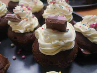 Mini cakes with cream, chocolate and sprinkles