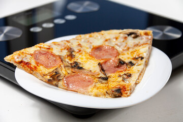 a piece of pizza on a white plate and a pink centimeter on black scales on white background