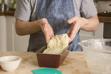 A man without a face in an apron holds raw bread dough in his hands, a home baker. Authentic home cooking hobby